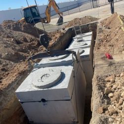 A septic system being lowered into ground by a crane.