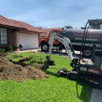 A Bobcat digging up a front lawn.